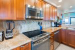 The kitchen features granite countertops, wood cabinets, and all stainless steal appliances including dishwasher, stove/oven, fridge/freezer, and microwave